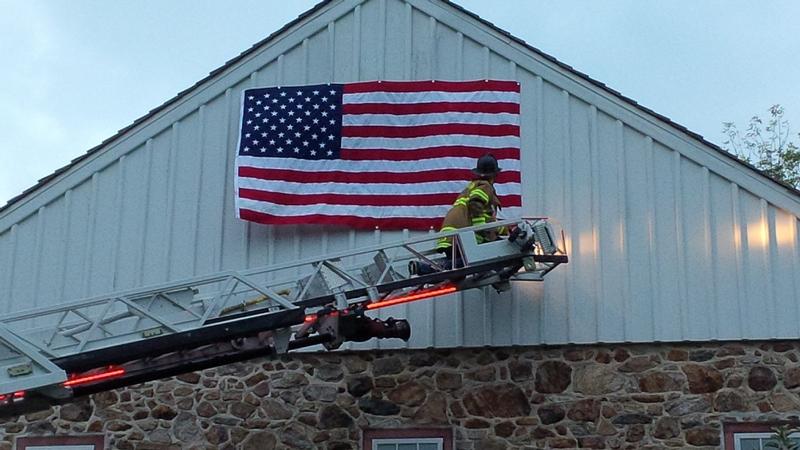 Malvern Fire Fighter hangs a flag on a Willistown Township Barn